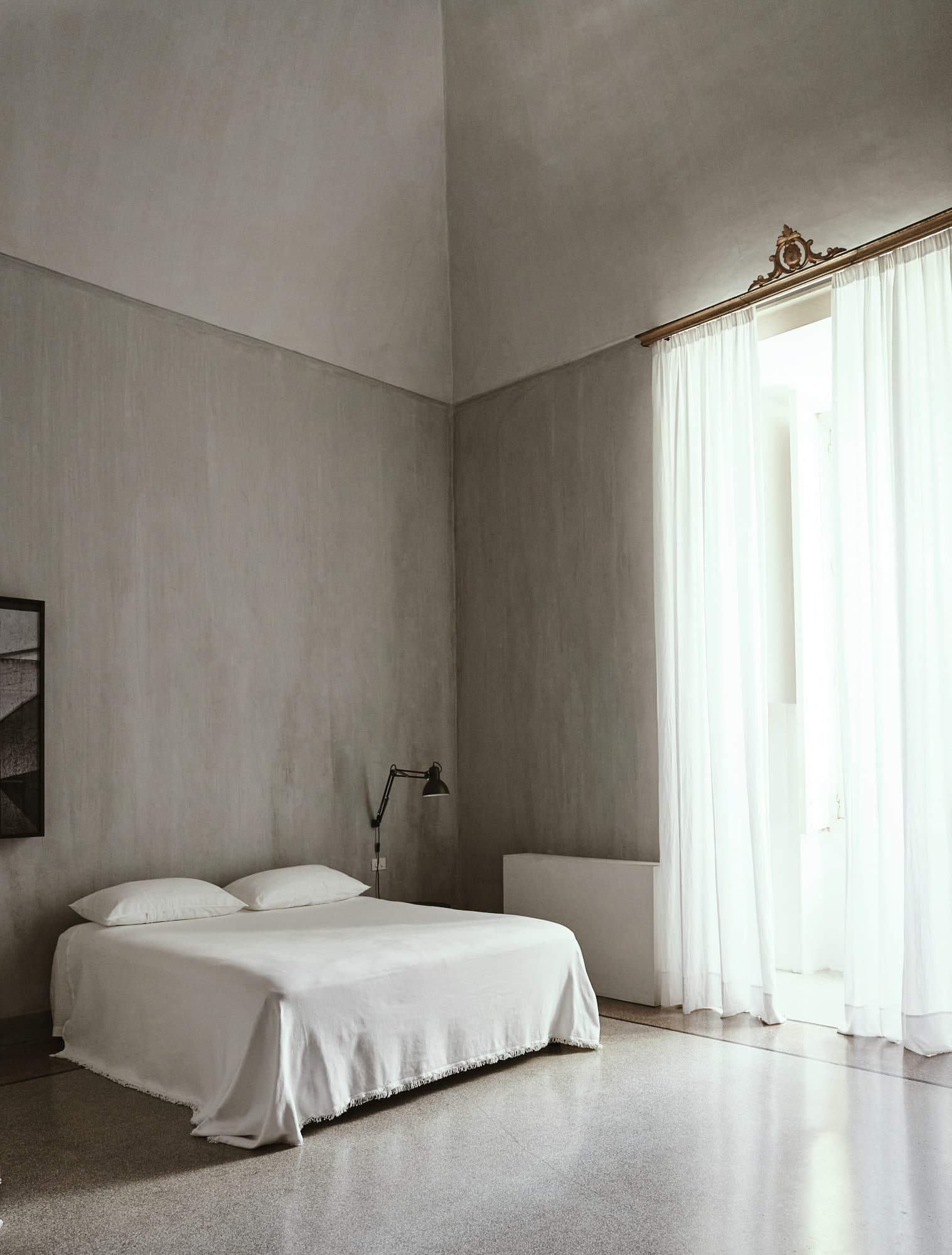 White bedroom with sheer curtains and bare walls